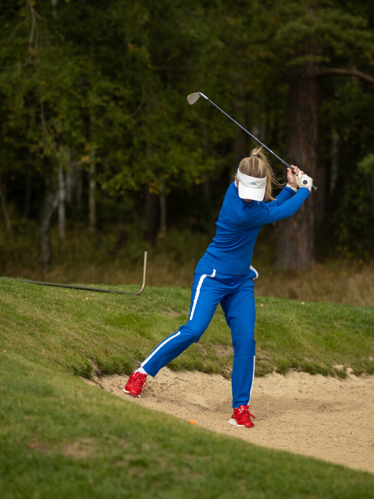 Hráčka golfu odpaľuje loptičku z pieskovej duny