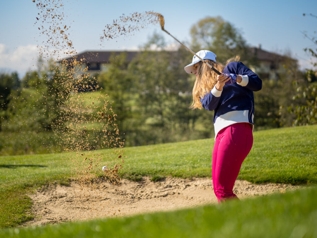 Hráčka golfu odpaľuje loptičku z pieskovej duny