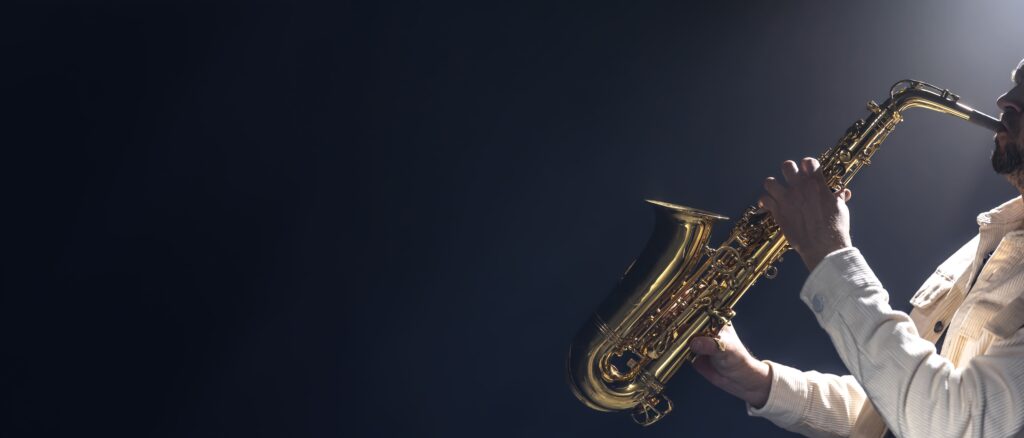 young man plays saxophone saxophonist dark background (1)
