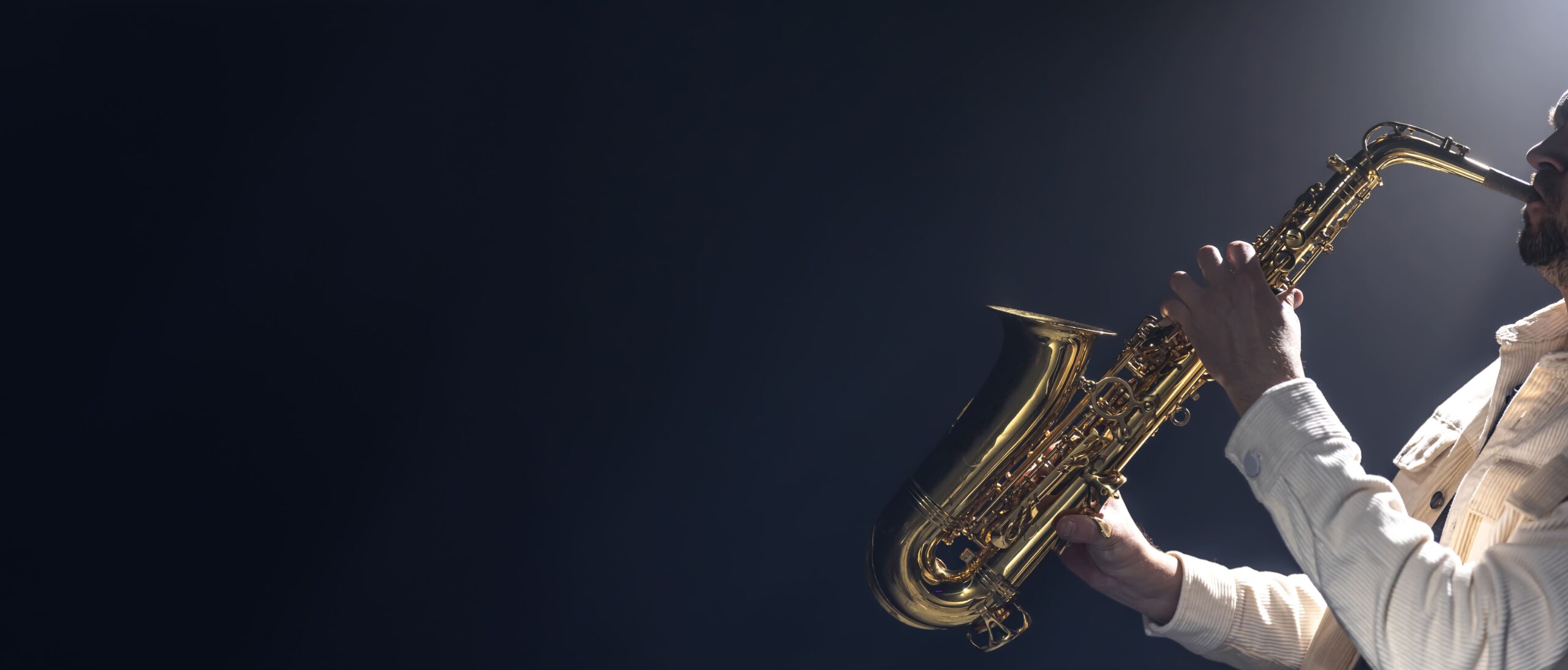 young man plays saxophone saxophonist dark background (1)